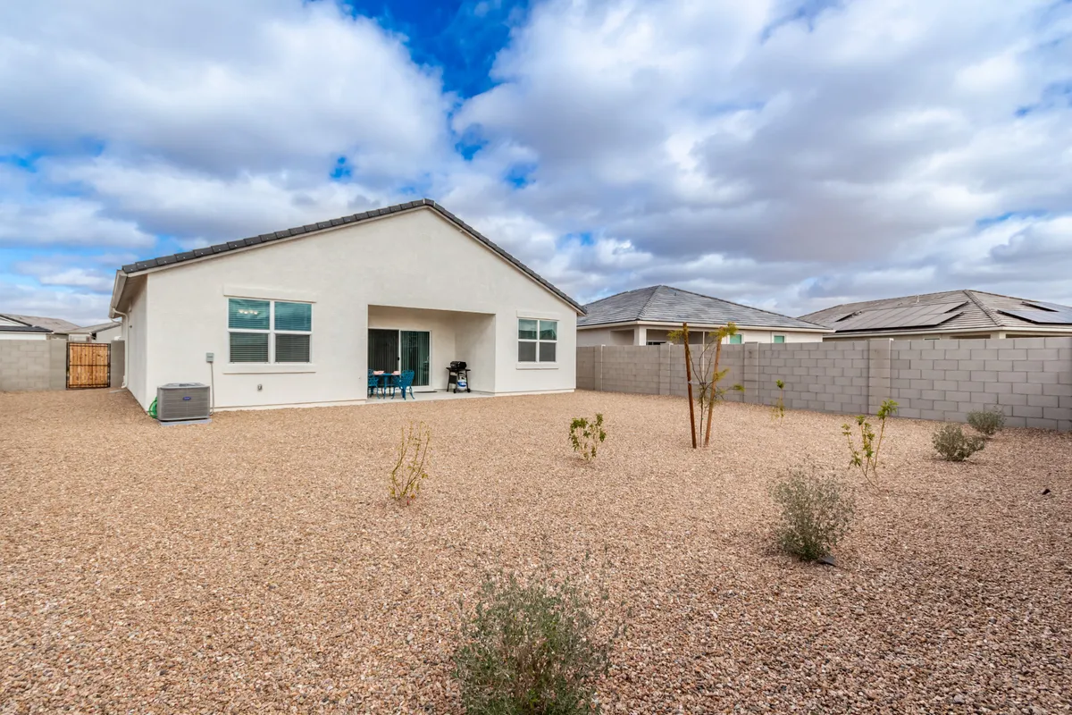 Featuring a broad perspective of the backyard, house facade, and patio area, this image highlights the connection between indoor and outdoor living. The tranquil scene invites viewers to imagine seasonal gardening, outdoor dining, or simply unwinding while enjoying the sunset.