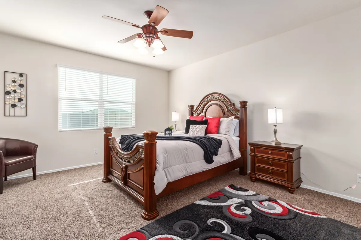 A comfortable bedroom featuring an ornate wooden bed with colorful bedding, a stylish area rug, and nightstands with lamps on either side. The space has a warm, welcoming ambiance suitable for restful nights or a peaceful retreat.