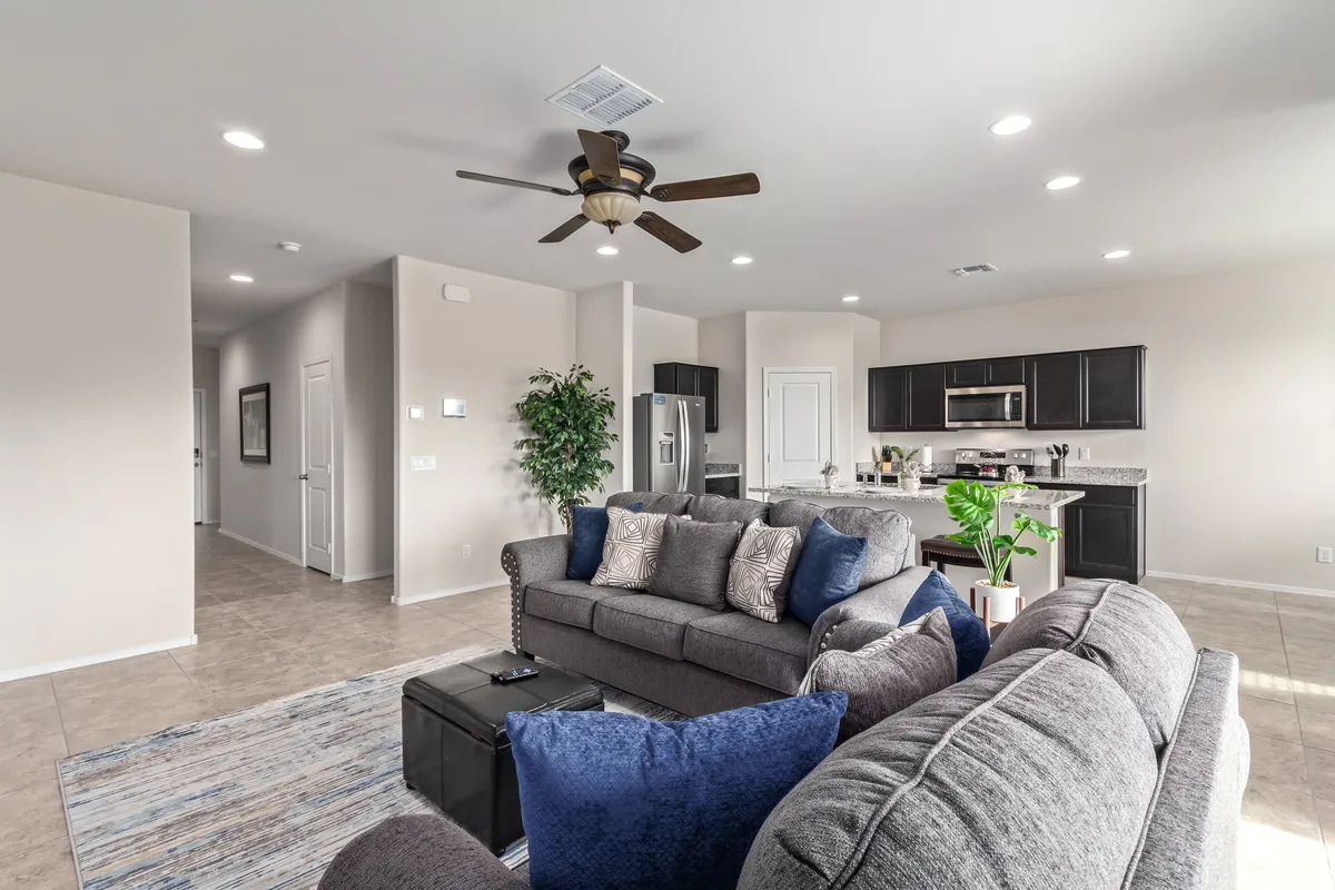 An inviting open-plan space with a sofa and coffee table flowing into a modern kitchen area. Designed for both relaxation and entertaining, the scene features a decorative plant that adds a homely touch, with ample space for social gatherings, holiday celebrations, and daily family life.